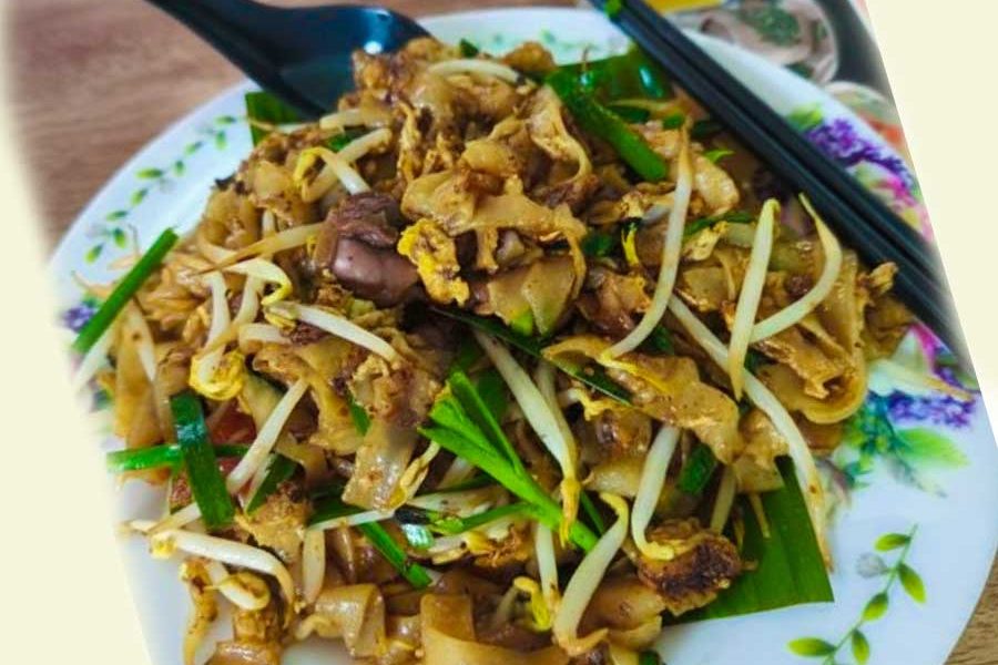 A plate of classic Malaysian Char Kway Teow with fresh bean sprouts, chives, and cockles